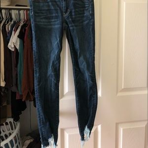 dark blue jeans with distressed bottoms